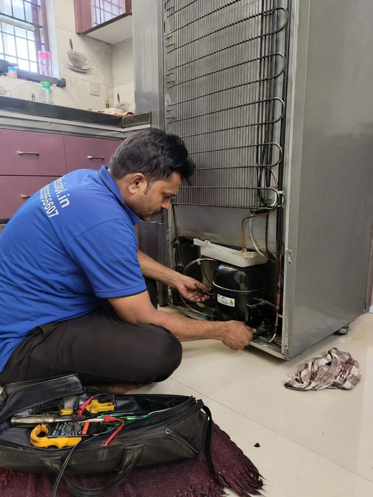 Technician inspecting faulty refrigerator compressor in Hyderabad home kitchen
