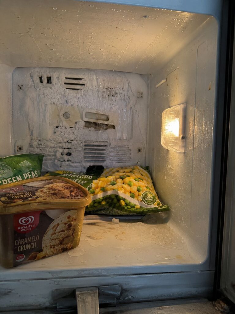 Close-up of freezer light on but not cooling with melting frozen food inside refrigerator