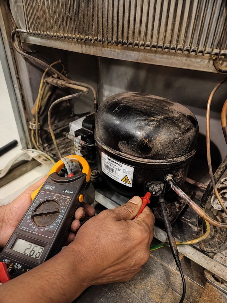 Close-up of overheated refrigerator compressor during repair inspection