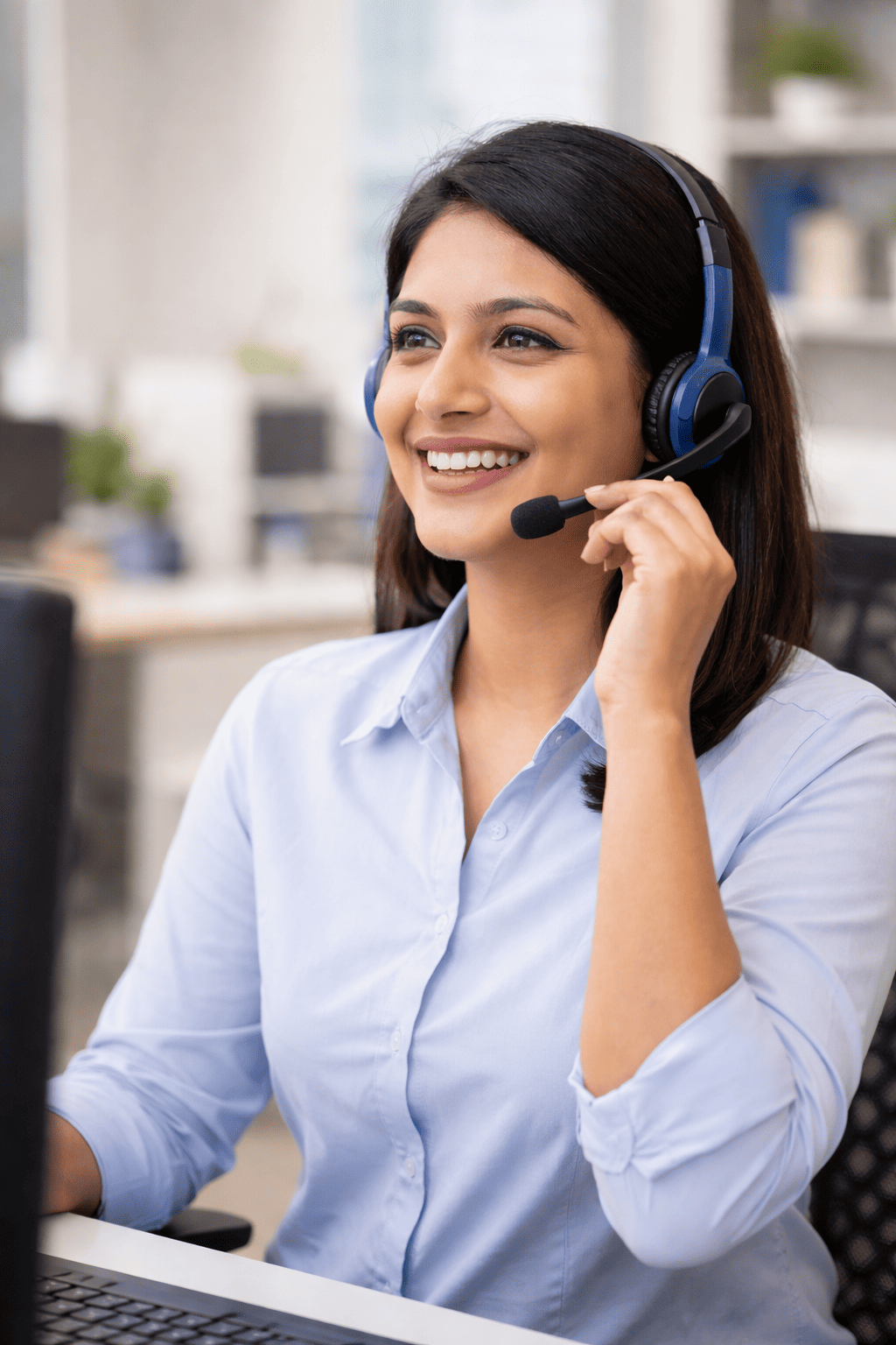 Smiling customer support executive wearing a headset and talking to customers from an office in Kolkata